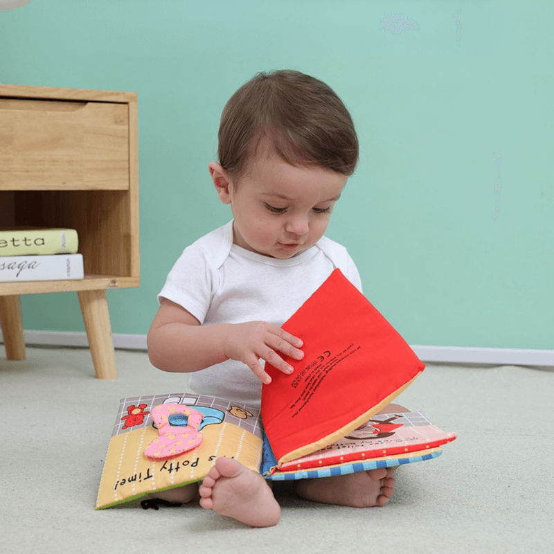 Little boy scrolling trough a baby soft book with a potty training colorful themes. 