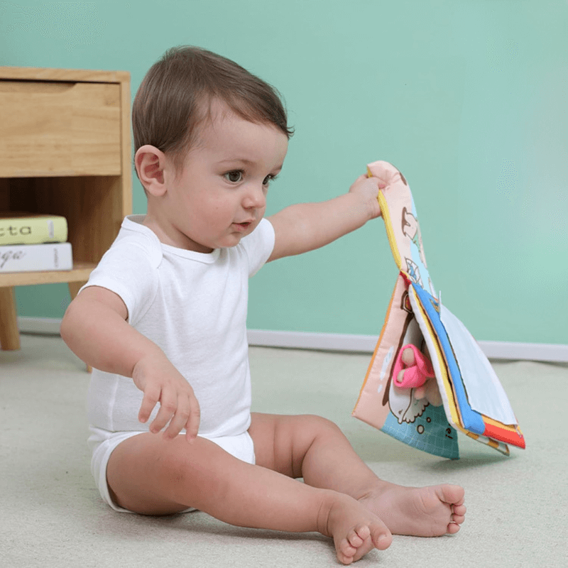 Baby boy sitting and holding his soft Potty Buddy Book. 