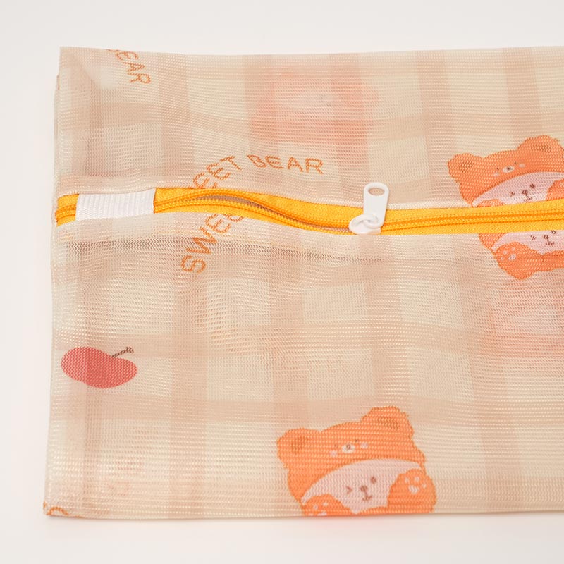 Close up on the mesh zip bag with bears and apples pattern. 