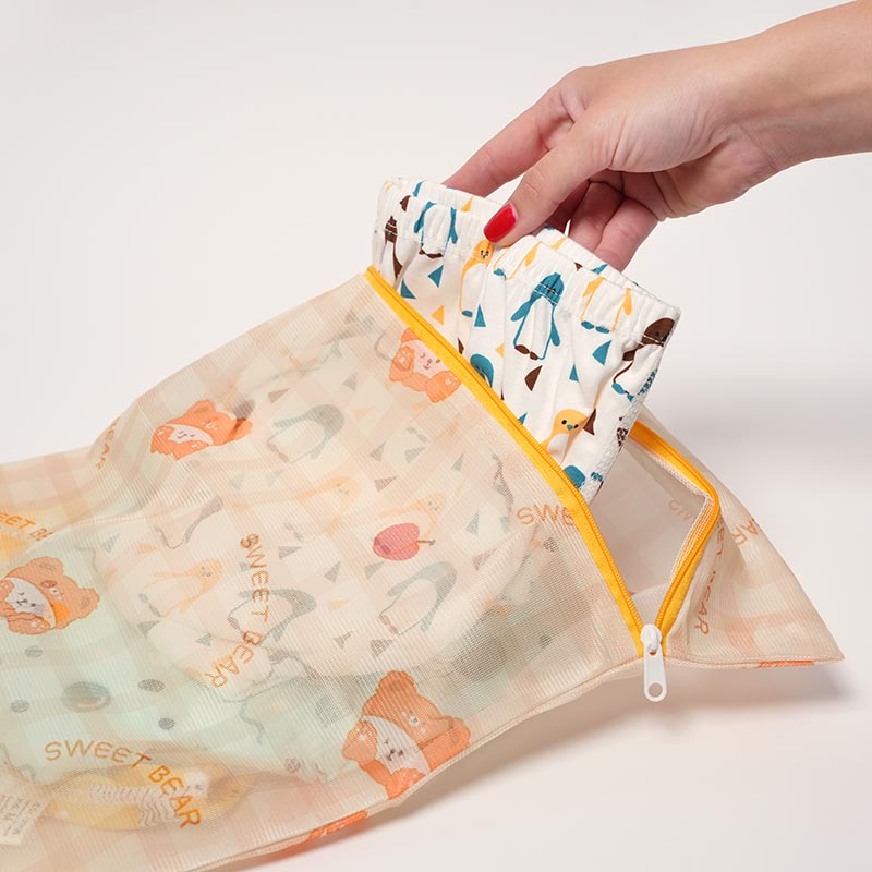 Woman's hands placing Loondie Potty Undies inside a CleanPouch Zip Bag so they can be cleaned in the washing machine. 