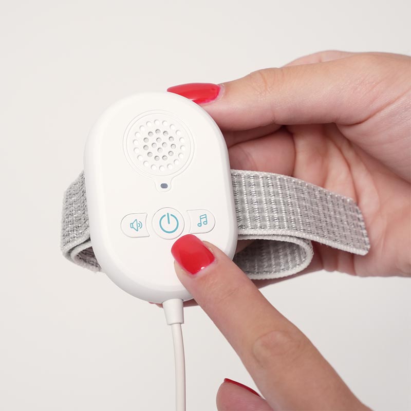 A hand showing a power button on the Loondie DreamDry Alarm. 