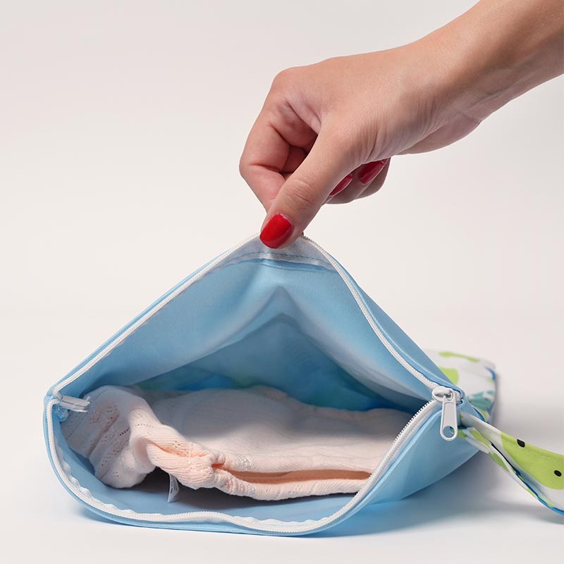 Woman's hand opening the DuoDry Wet Bag to show Loondie Potty Undies stored inside.