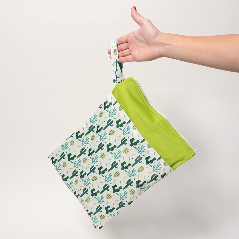 A hand holding a leak-proof DuoDry Wet Bag Cactus version. 