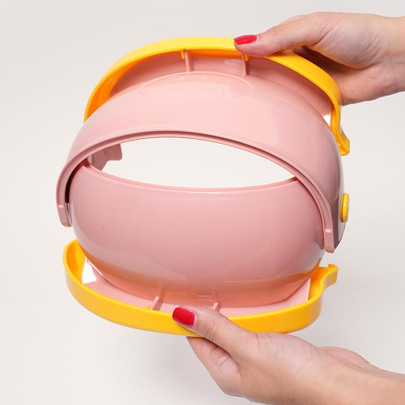 Woman's hands holding a foldable pink potty. 