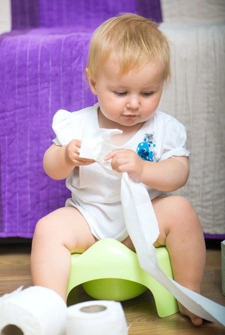 Kid playing with a roll of toilet paper on a potty