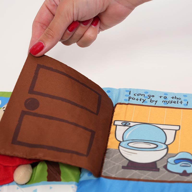 A hand flipping a page of the potty training soft book. 