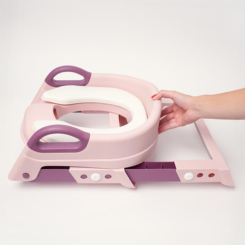 Woman holding a pink potty training StepUp Seat. 