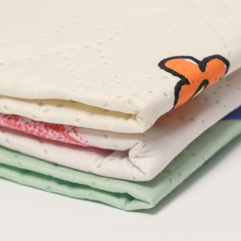 Close up on three versions of the Waterproof Dream Mat stacked together. 