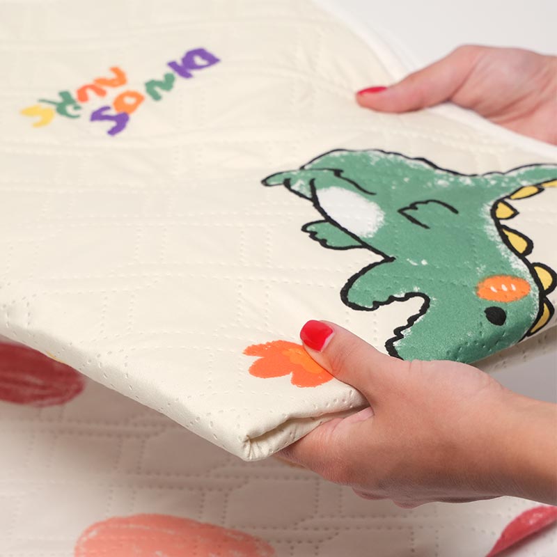 Woman holding the absorbent overnight waterproof mat with Dino design. 
